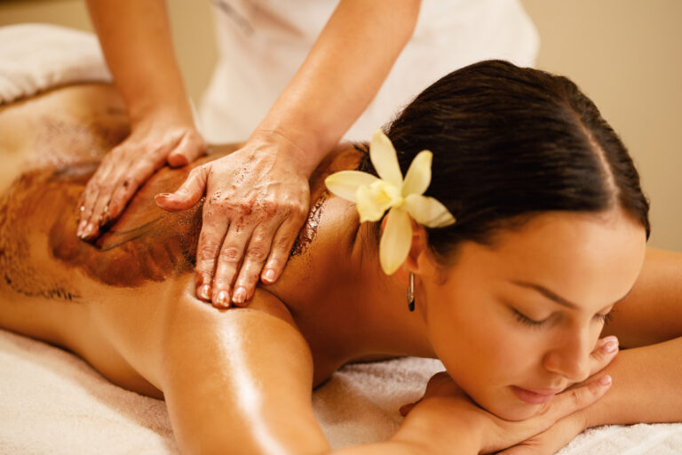 Close-up therapist massaging woman's back during hot chocolate spa treatment.